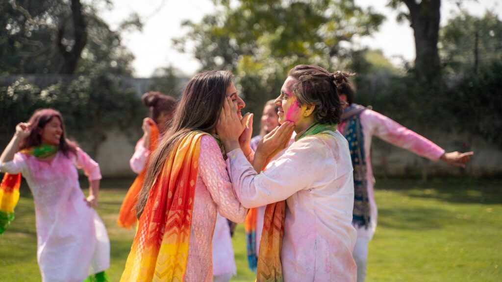 Adults playing with colorful powders during a lively outdoor Holi festival, enjoying the festive spirit.