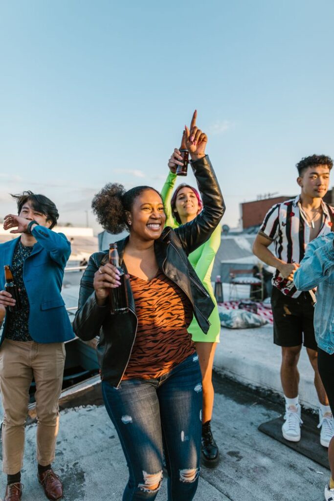 A group of diverse young adults enjoying a lively rooftop party under a clear blue sky.
